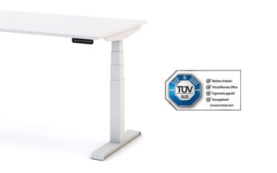Ein höhenverstellbarer Schreibtisch Modell 'JUNIOR' mit Holzplatte und Beinen aus weißem Metall, der mit einem Bedienfeld ausgestattet ist. Neben dem Schreibtisch befindet sich eine TÜV SÜD-Zertifizierungsplakette, die auf geprüfte Sicherheit und ergonomisches Design hinweist.